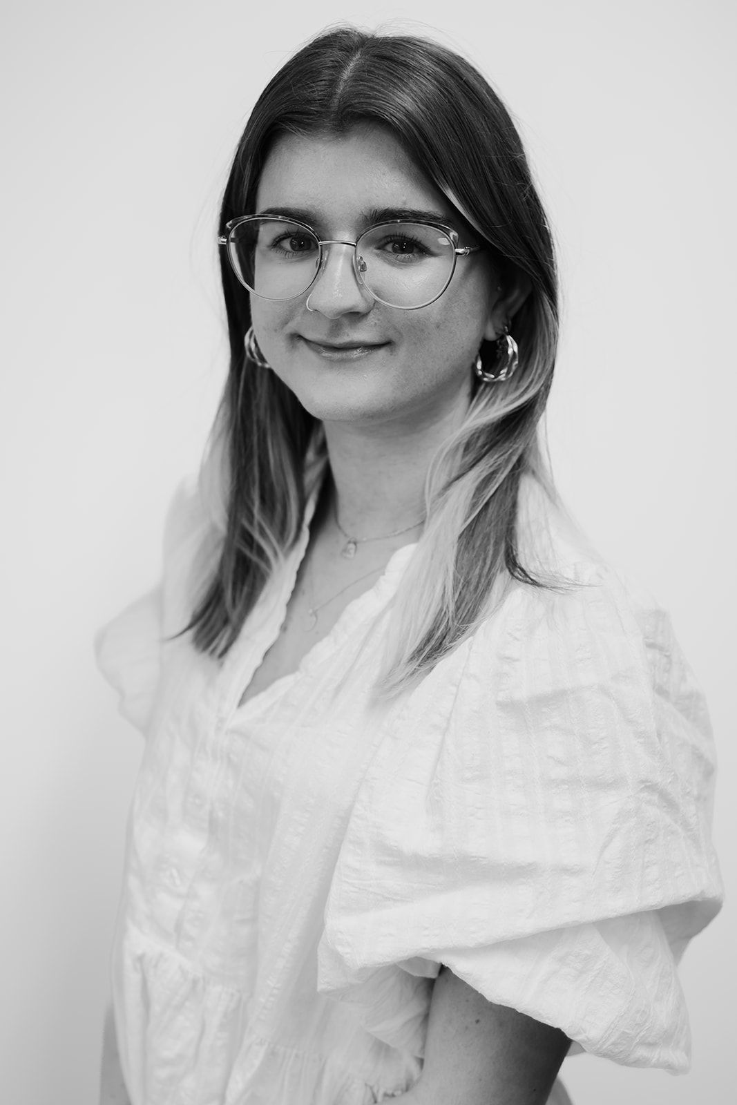 Woman wearing glasses and white blouse smiling