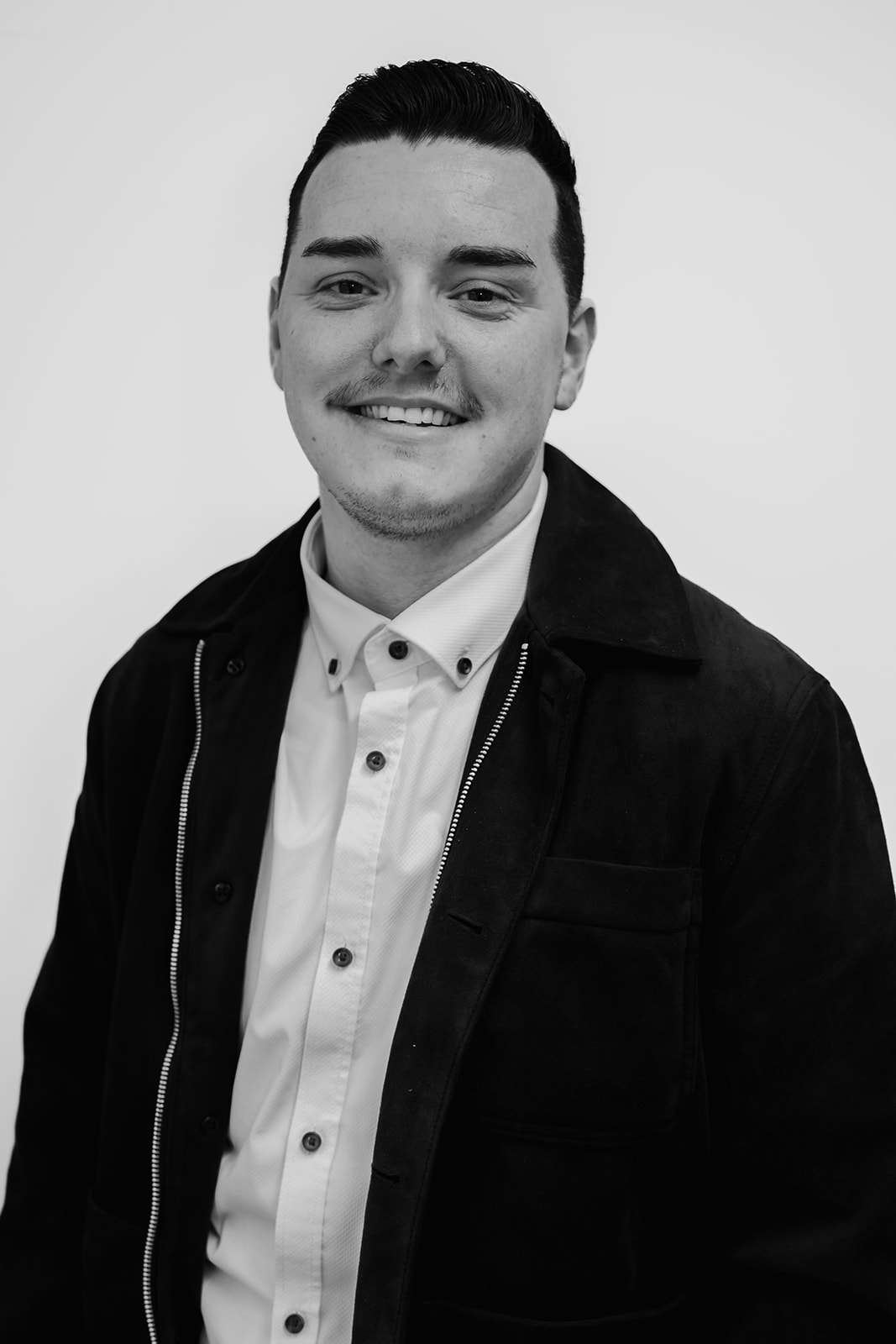 Man smiling in a black and white portrait.