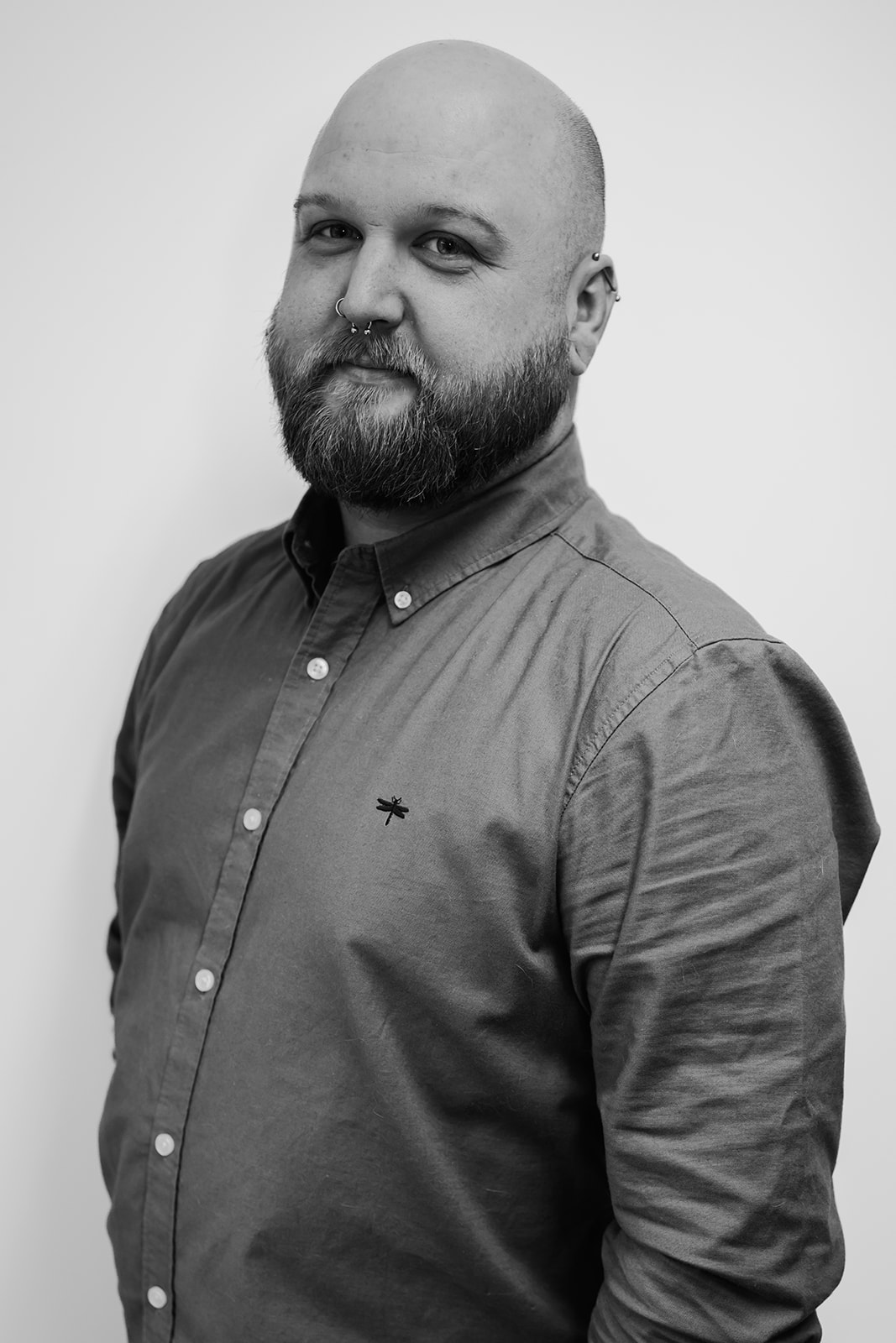 Man with beard and piercings, black and white photo.