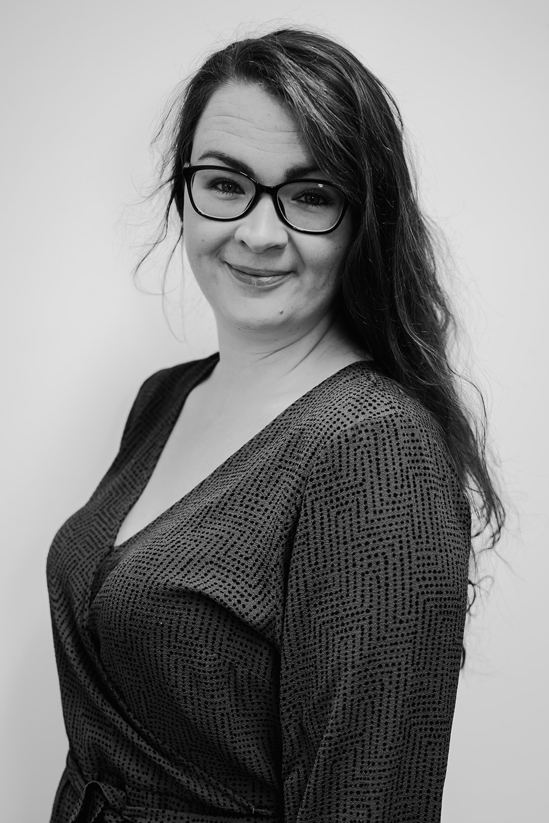 Smiling woman with glasses, monochrome portrait.