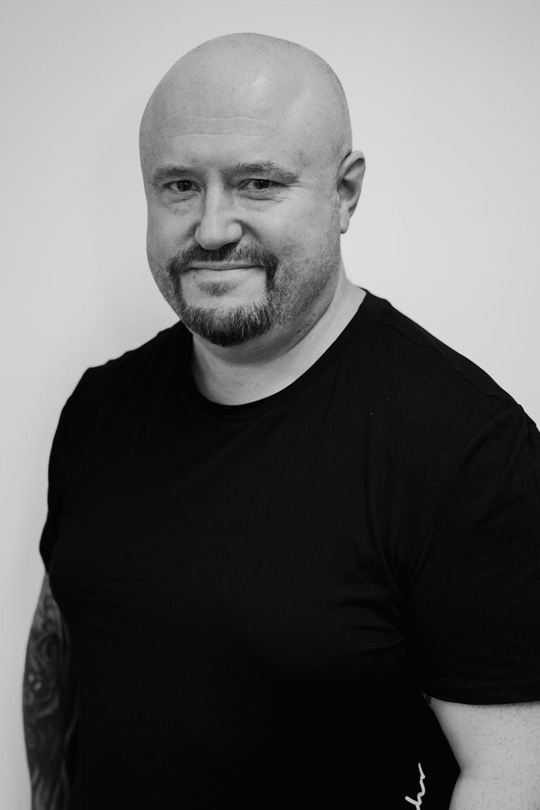 Smiling bald man in black shirt, portrait photo.