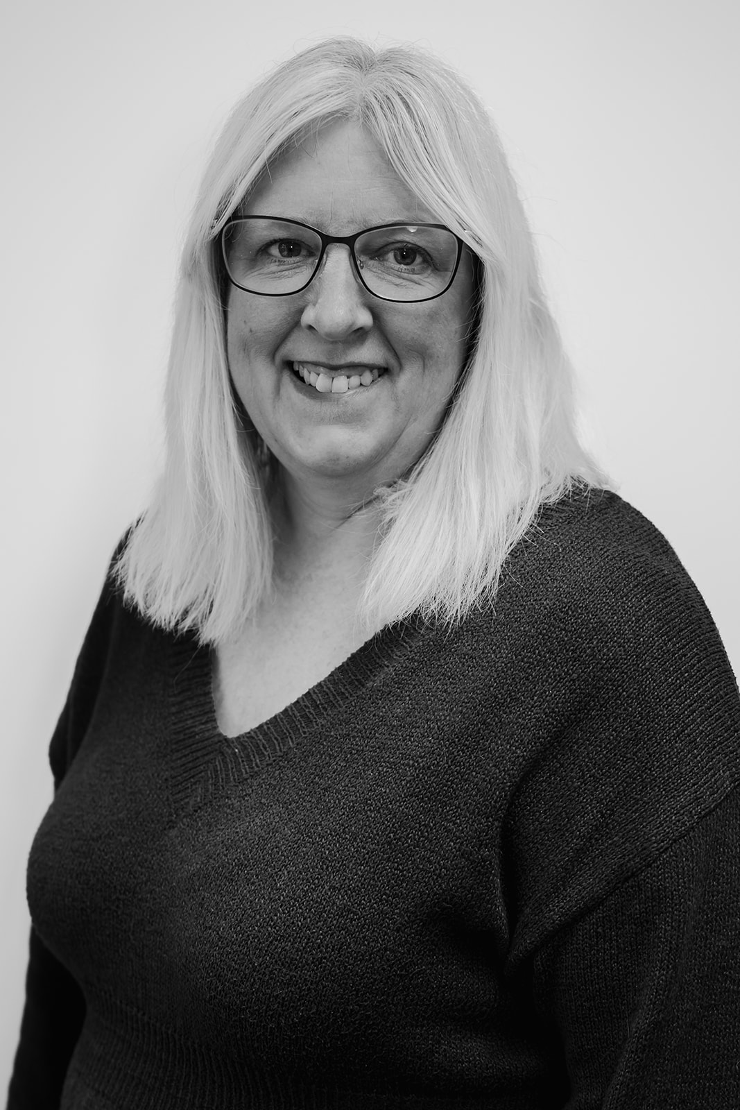 Smiling woman with glasses, portrait in black and white.