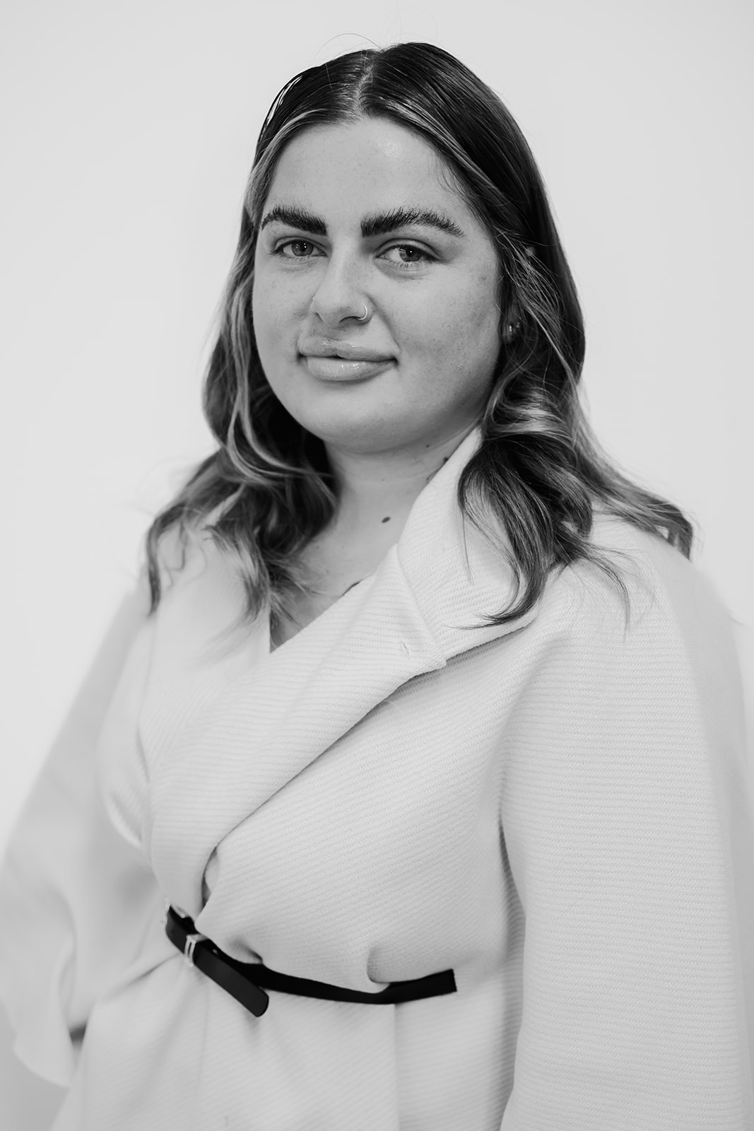 Person in white jacket, smiling, black and white photo.