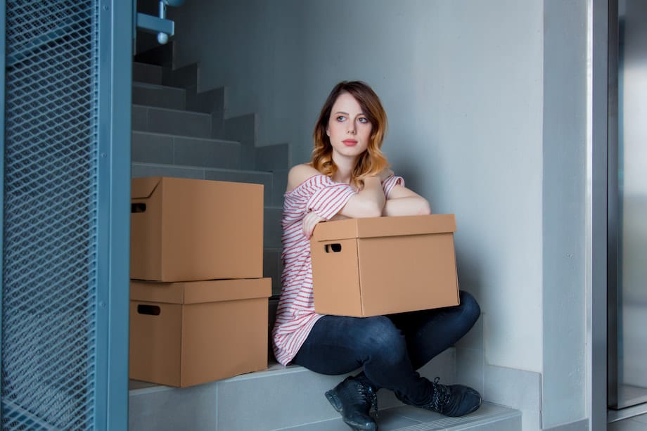 Woman with moving boxes sitting on stairs